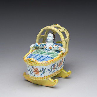 A polychrome Dutch Delft model of a cradle with child, 19th C.