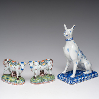 A blue and white Dutch Delft model of a seated dog and a pair of polychrome cows, 19th C.