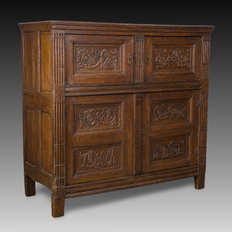 A Flemish carved oak four-door cupboard with panels showing spitting griffins, 17th C.