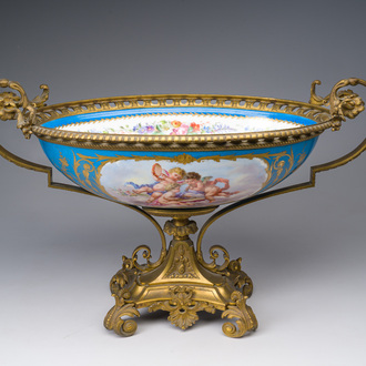 Een grote Franse ovale Sèvres-stijl goudgehoogde kom met 'bleu céleste' fondkleur, floraal decor, putti en verguld bronzen monturen, 19de/20ste eeuw