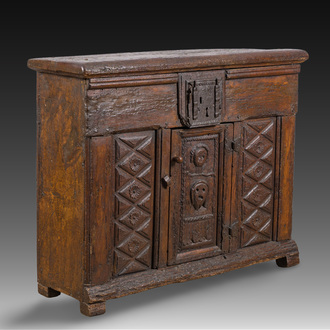 A carved oak one-door cupboard with the central panel carved with two heads, probably Germany, 16th C.