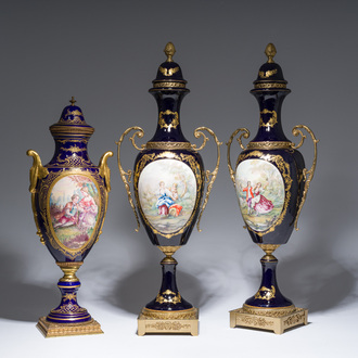 Three French gold layered blue ground gilt bronze mounted Sèvres style vases and covers with gallant scenes, 20th C.