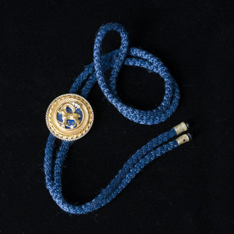 An 18 carat white and yellow gold Texan tie with a capricorn finished with diamonds (0,15 carat) and lapis lazuli, 20th C.