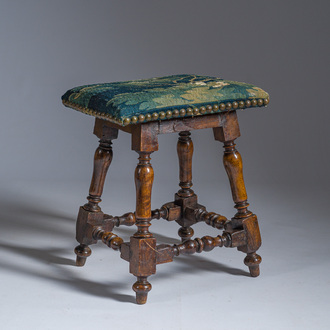 A wooden stool with turned legs upholstered with a fragment of a Flemish wall tapestry, 17th C.