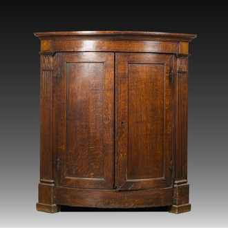 A Flemish Empire style carved oak two-door corner cupboard, 19th C.