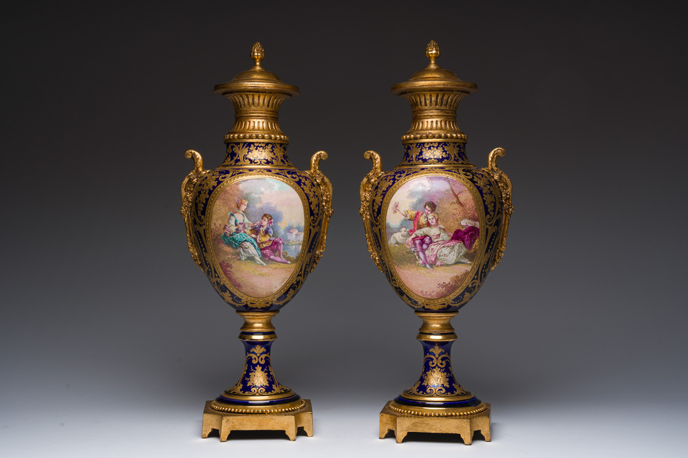 Paire de vases couvertes &agrave; fond bleu royale &agrave; la mani&egrave;re de S&egrave;vres aux montures dor&eacute;es et &agrave; d&eacute;cor de sc&egrave;ne d'amour, France, 20&egrave;me si&egrave;cle