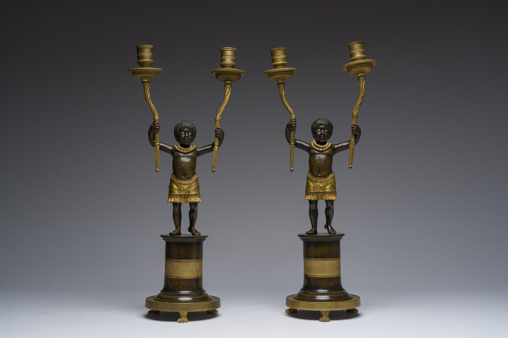 Een paar Franse verguld en gepatineerd bronzen Directoire kandelaars met twee lichtpunten in de vorm van toortsdragende Afrikanen, eind 18de eeuw