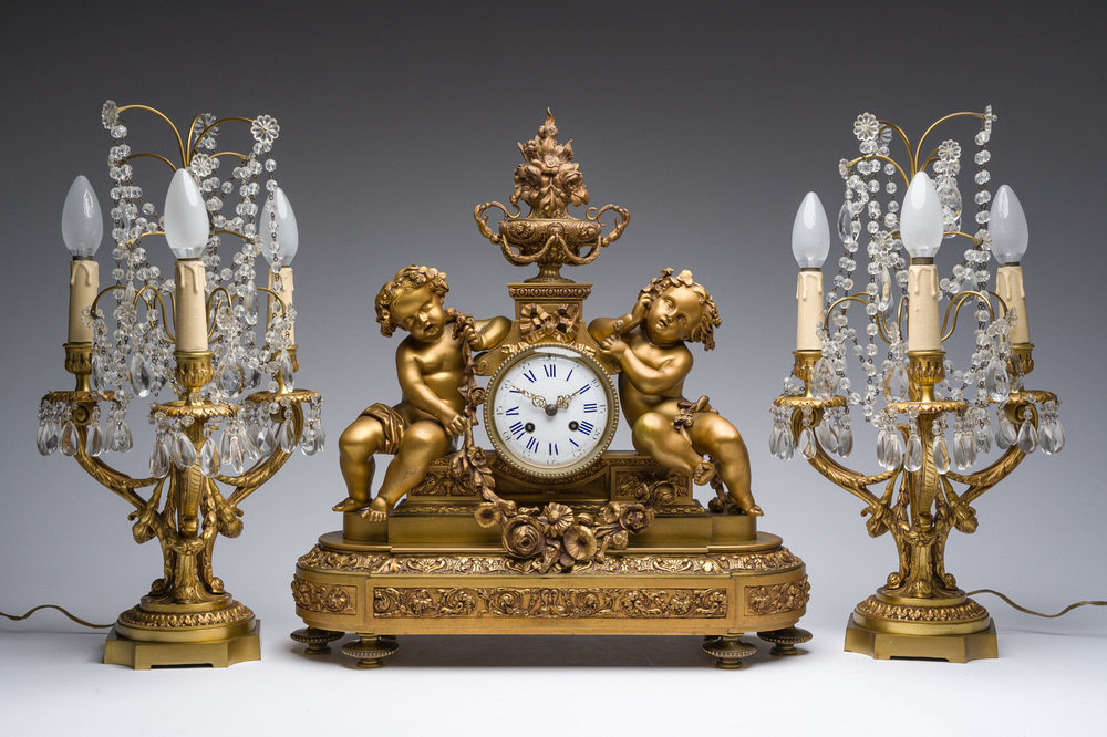 Garniture de chemin&eacute;e en trois pi&egrave;ces en bronze dor&eacute; &agrave; d&eacute;cor floral et de putti, France, 19&egrave;me/20&egrave;me si&egrave;cle