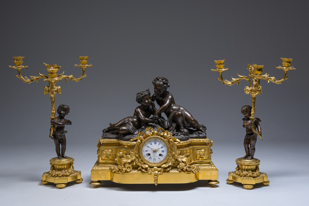 Garniture de chemin&eacute;e en trois pi&egrave;ces en bronze patin&eacute; et dor&eacute; couronn&eacute;e de deux putti avec un nid d'oiseau, France, 19&egrave;me si&egrave;cle