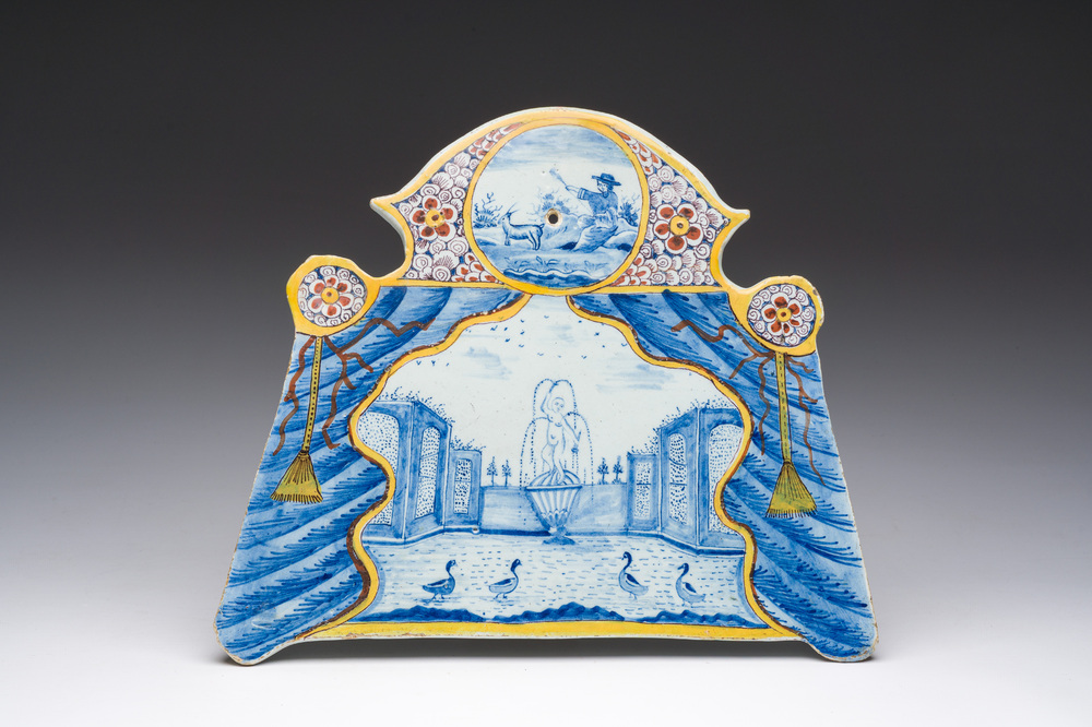 Een polychrome Delftse plaquette met een fontein in theatrale gordijnlijst, 18de eeuw