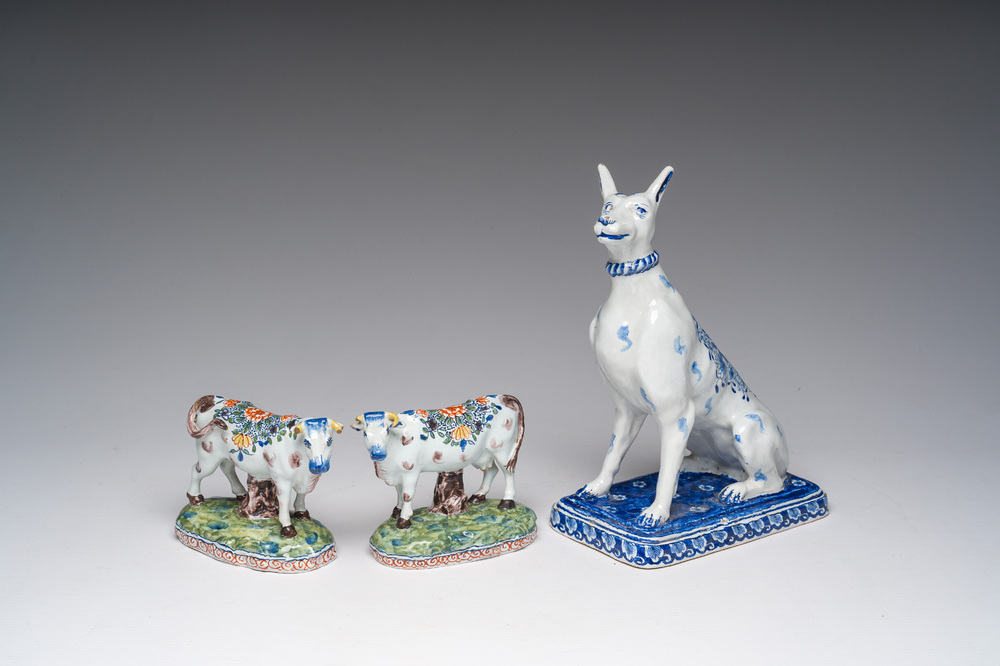 A blue and white Dutch Delft model of a seated dog and a pair of polychrome cows, 19th C.
