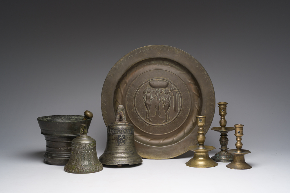Two bells, a mortar and stamper, three candlesticks and an alms dish in bronze and brass, 17th/19th C.