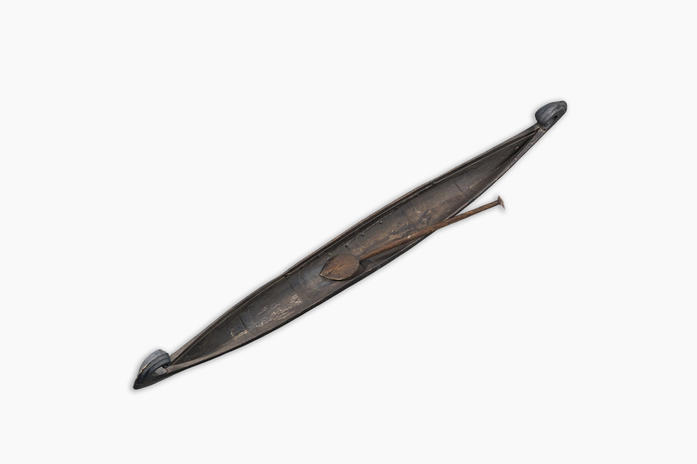 A large Indian wooden Kerala snake canoe with a curled stem and stern with accompanying paddle, 20th C.