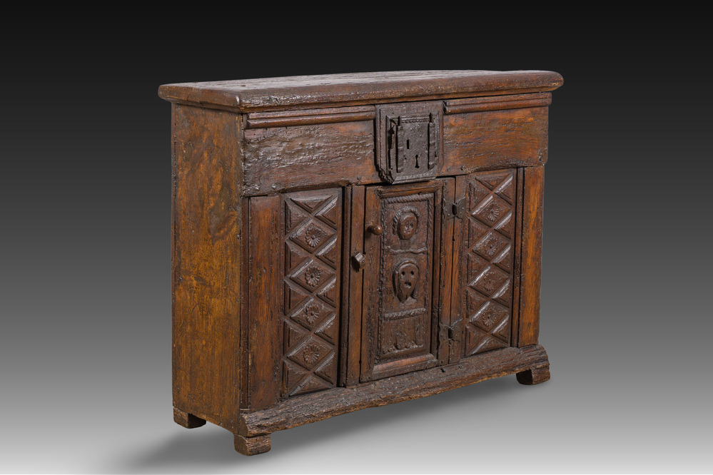 A carved oak one-door cupboard with the central panel carved with two heads, probably Germany, 16th C.