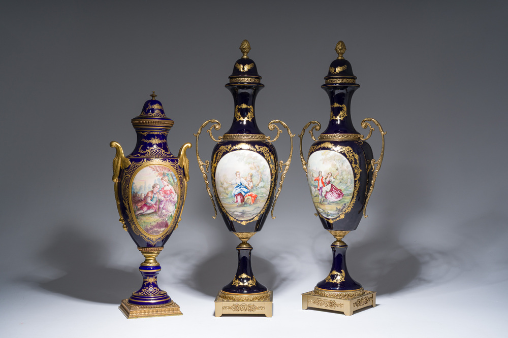Three French gold layered blue ground gilt bronze mounted S&egrave;vres style vases and covers with gallant scenes, 20th C.