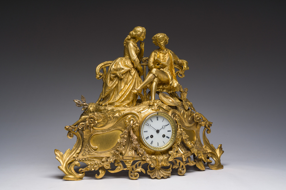 A French gilt bronze mantel clock crowned by a couple in love chatting on a bench, 19th C.