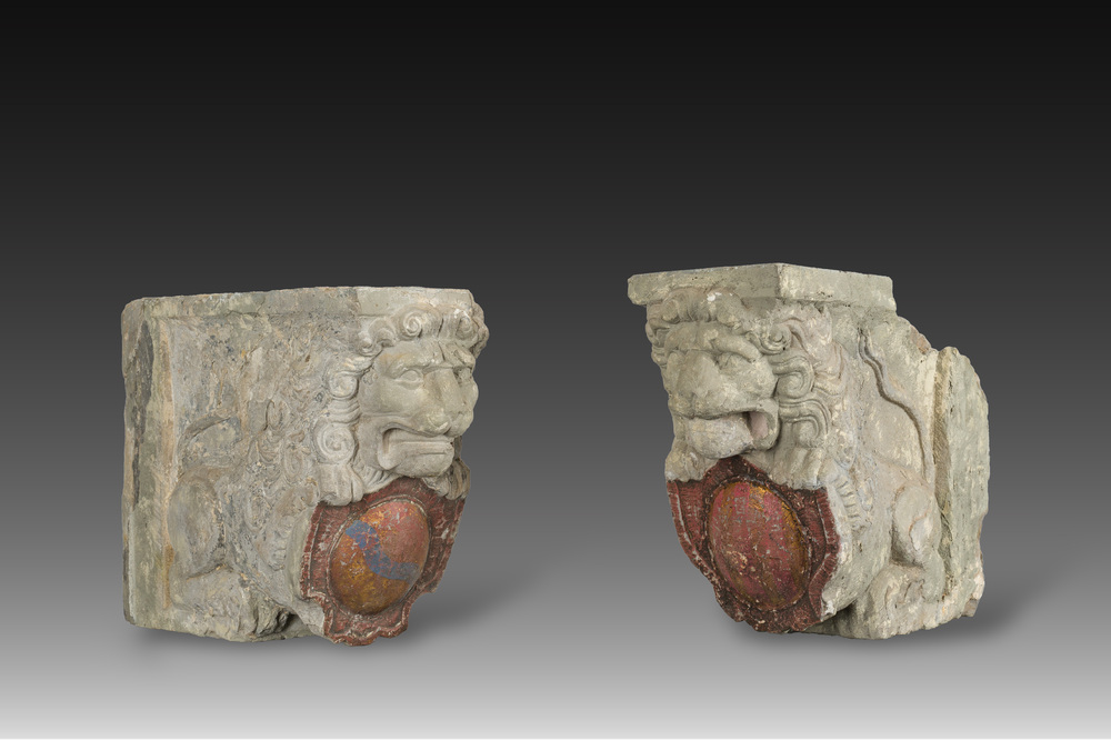 A pair of partly polychromed stone beam supports in the shape of lions holding coats of arms, probably Flanders, 16th/17th C.