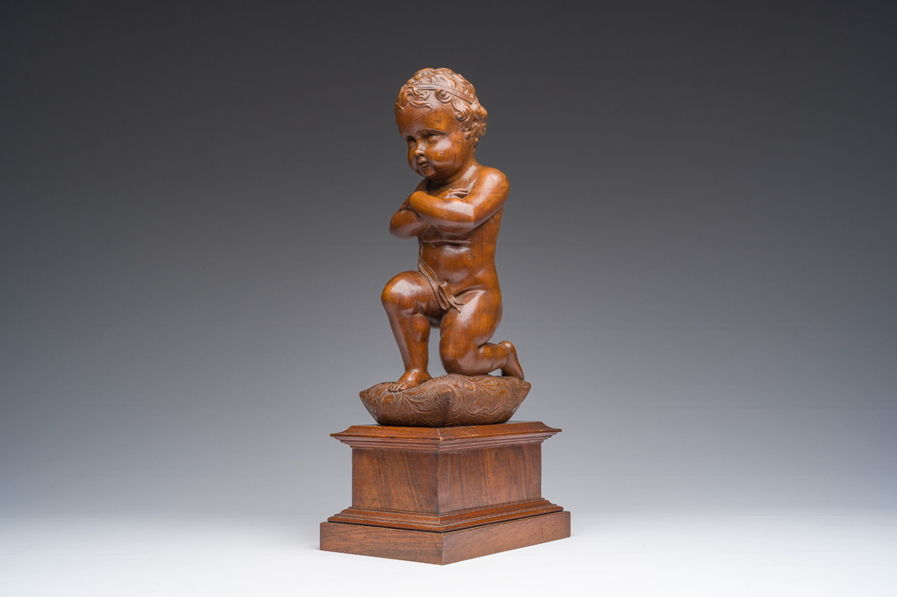 An Italian walnut sculpture of a youth kneeling on a cushion with floral design, 19th C.