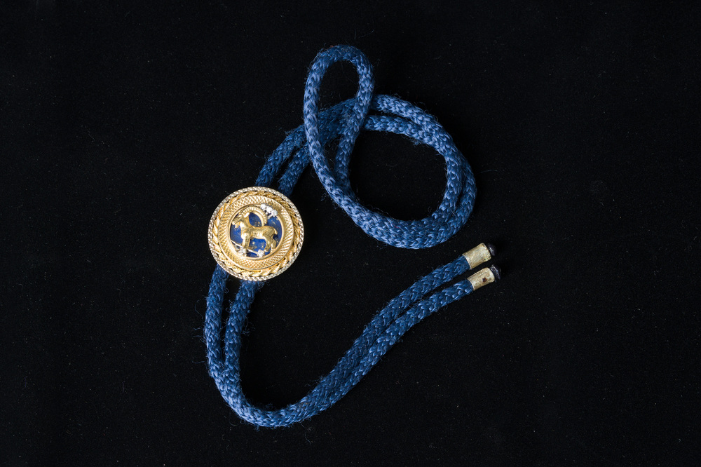 An 18 carat white and yellow gold Texan tie with a capricorn finished with diamonds (0,15 carat) and lapis lazuli, 20th C.