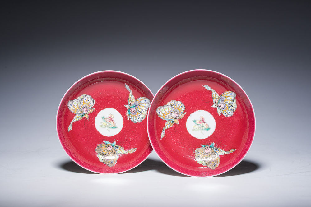 Een paar Chinese famille rose schotels met vlinders op een robijnrode fondkleur, 19de/20ste eeuw