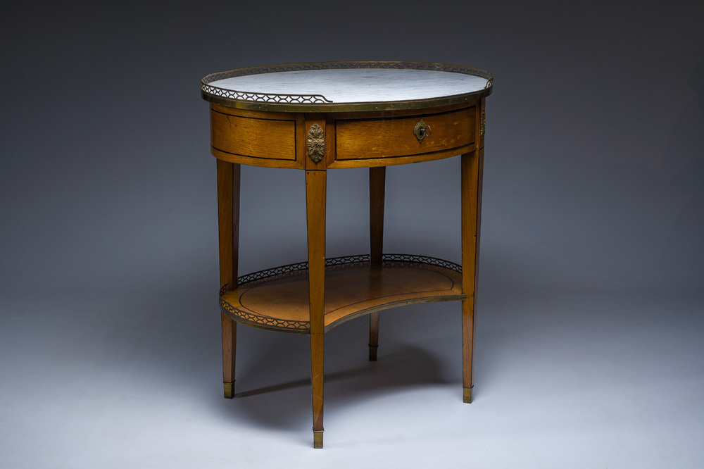 An oval French Louis XVI wooden writing table with gilt copper and brass mounts and a marble top, circa 1800