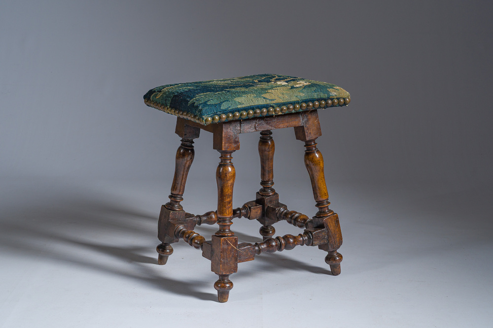 A wooden stool with turned legs upholstered with a fragment of a Flemish wall tapestry, 17th C.