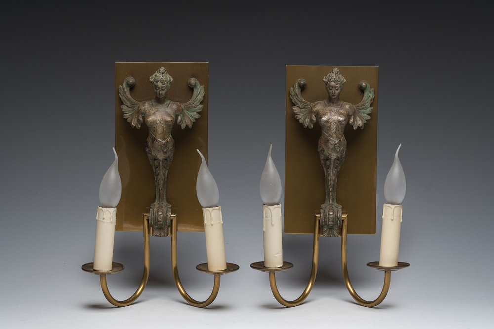 A pair of two-light wall lights in the shape of winged caryatids in patinated cast iron and brass, 20th C.