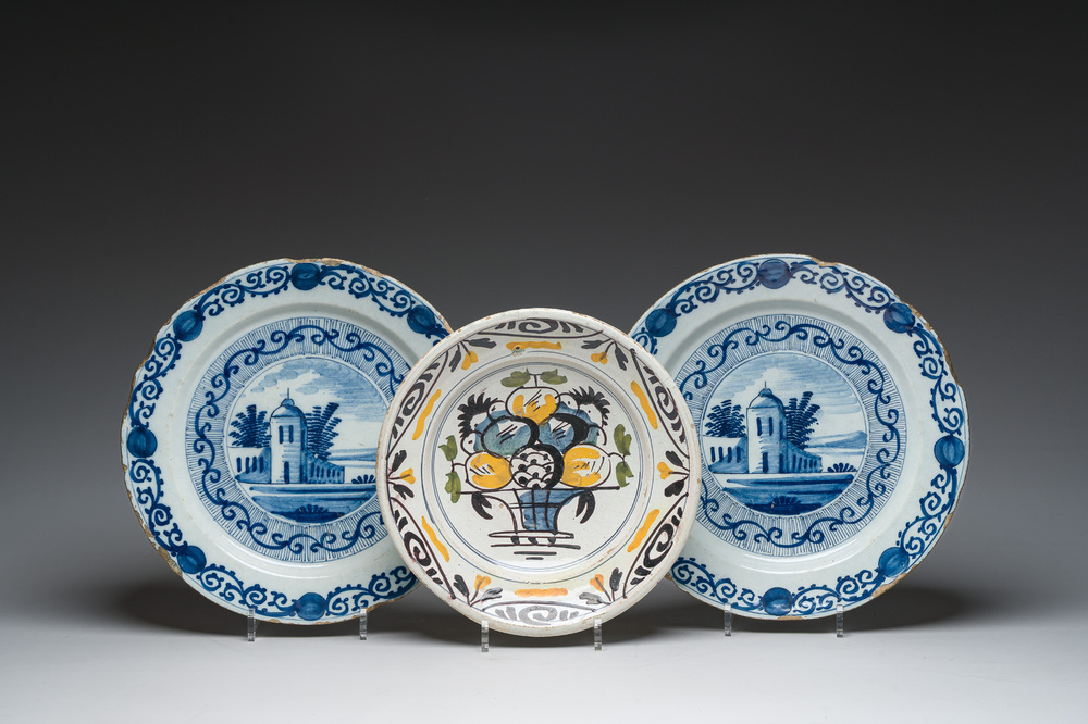 A pair of Dutch Delft blue and white dishes with a building in a landscape and a polychrome plate with a fruit basket, 18th/19th c.