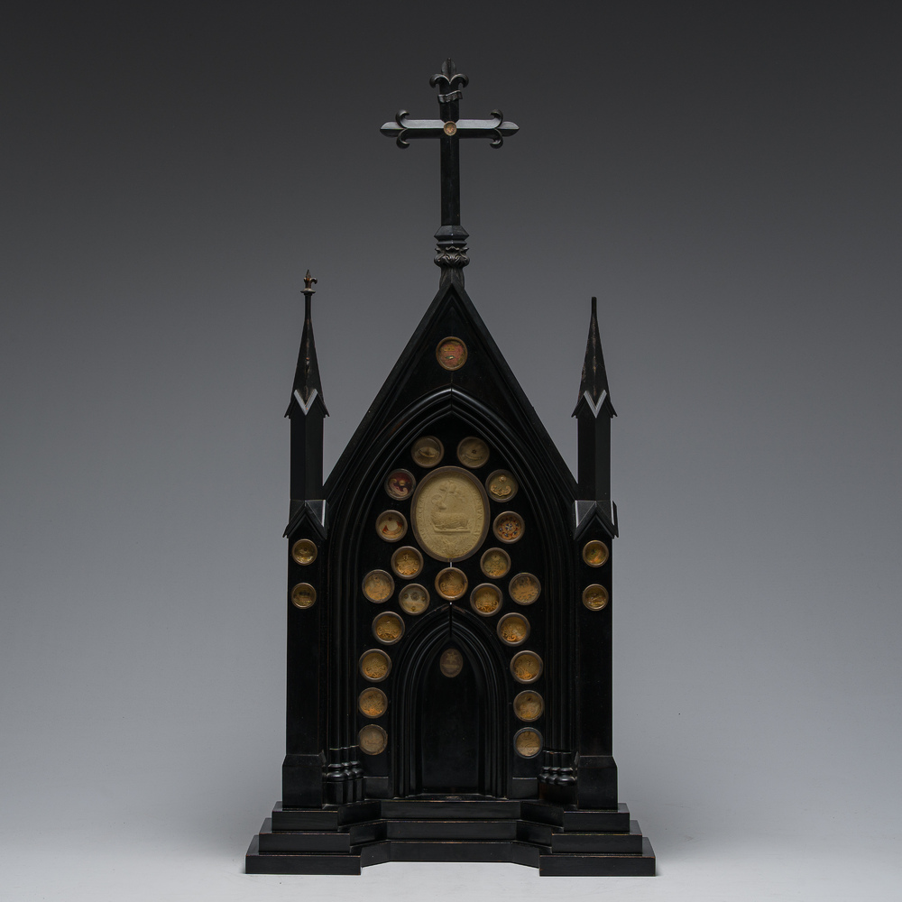 A large French Gothic Revival ebonized wooden cathedral-shaped reliquary with various relics, last quarter 19th C.