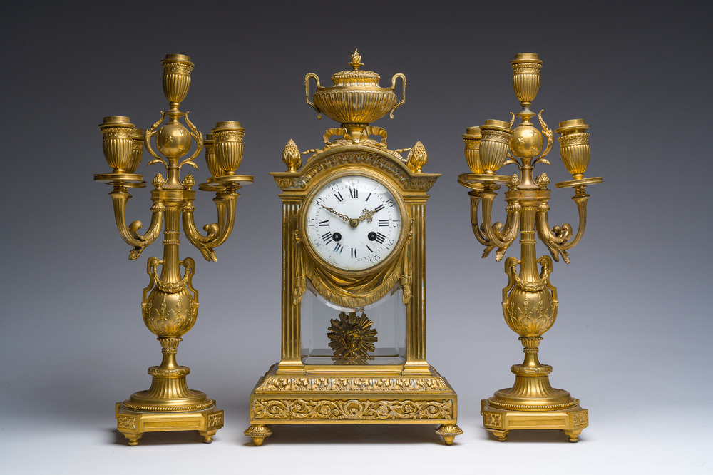 A French Louis XVI style gilt bronze and cut glass mantel clock accompanied by a pair of candlesticks, 19th/20th C.