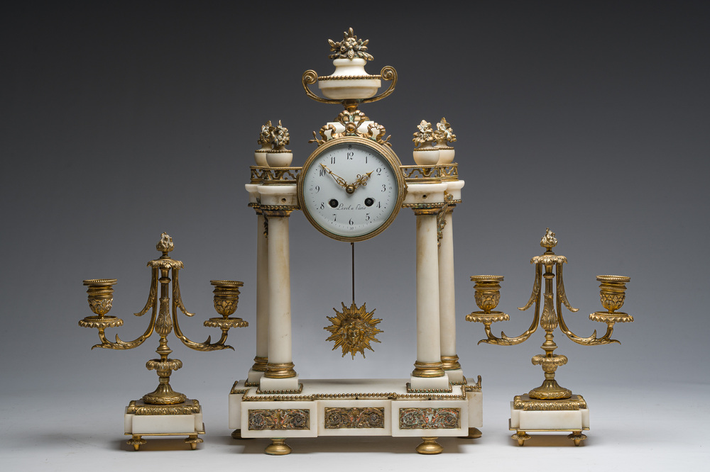 A French Louis XVI style three-piece gilt bronze mounted white marble clock garniture crowned with a flower basket, 19th C.