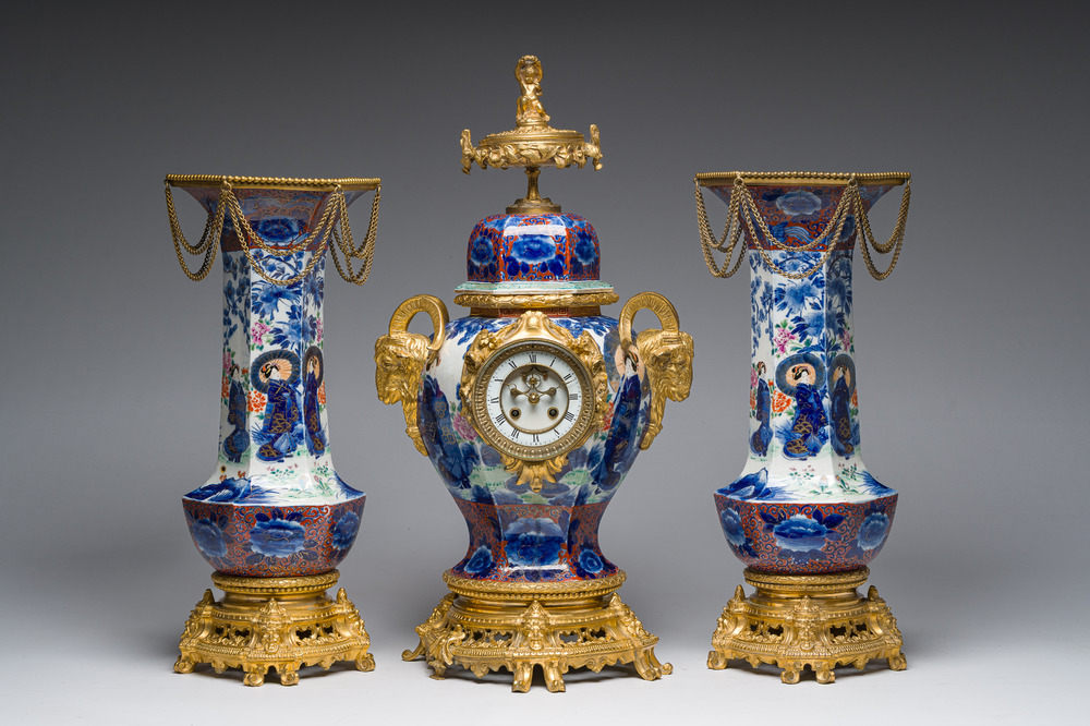 A Japanese polychrome three-piece garniture with ladies in a landscape mounted into a clock with richly gilt bronze mounts, 19th C.