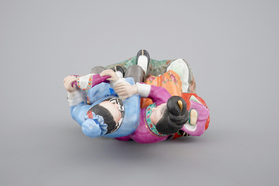 A Chinese porcelain model of an amorous couple, on wooden stand, 20th C.