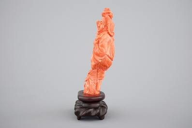 A Chinese carved red coral figure on a wooden stand, 19/20th C.