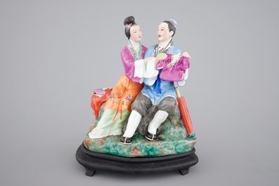 A Chinese porcelain model of an amorous couple, on wooden stand, 20th C.