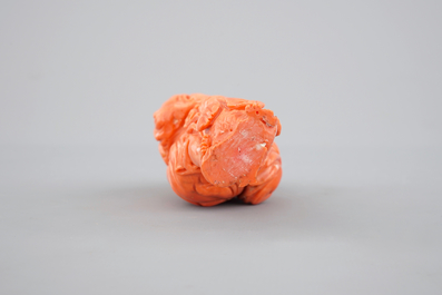 A Chinese carved red coral figure on a wooden stand, 19/20th C.