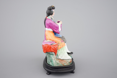 A Chinese porcelain model of an amorous couple, on wooden stand, 20th C.