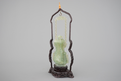 A Chinese carved green jadeite vase and cover on elaborate wooden stand, 19/20th C.