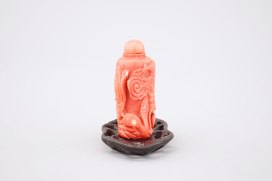 A Chinese carved red coral dragon snuff bottle on stand, 19th C.
