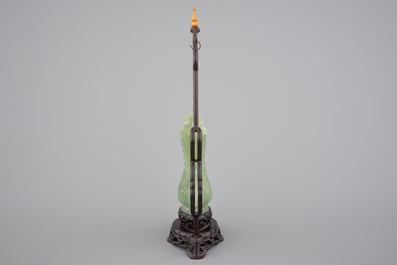 A Chinese carved green jadeite vase and cover on elaborate wooden stand, 19/20th C.