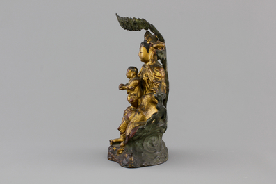 A Chinese bronze and gilt Buddha with child, seated beneath a bodhi tree, 17/18th C.