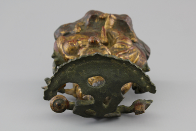 A Chinese bronze and gilt Buddha with child, seated beneath a bodhi tree, 17/18th C.