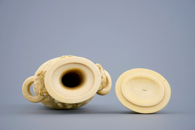 A Chinese carved ivory vase and cover on a wooden base, early 20th C.