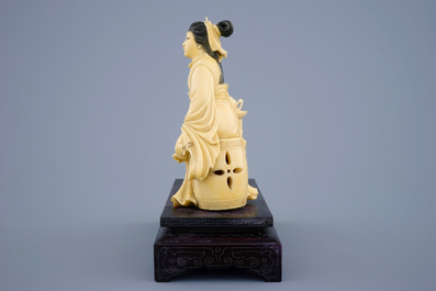 A Chinese carved ivory group of a lady near a tea table on a wood base, 19th C.