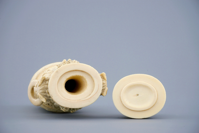 A Chinese carved ivory vase and cover on a wooden base, early 20th C.