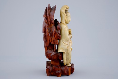 Une figure de Guanyin en pierre de savon sur socle en bois sculpt&eacute;, 18/19&egrave;me
