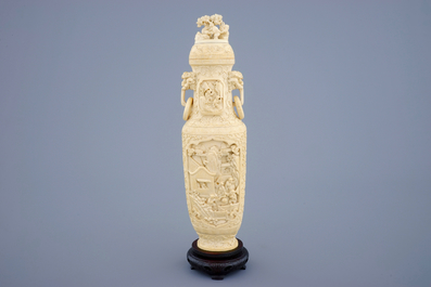 A Chinese carved ivory vase and cover on a wooden base, early 20th C.