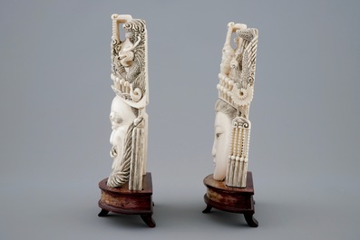 A pair of Chinese carved ivory faces on wooden stands, 19th C.