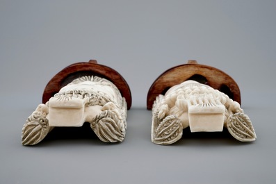 A pair of Chinese carved ivory faces on wooden stands, 19th C.