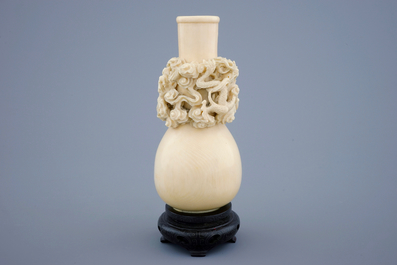 A Chinese carved ivory dragon vase on a wooden base, early 20th C.